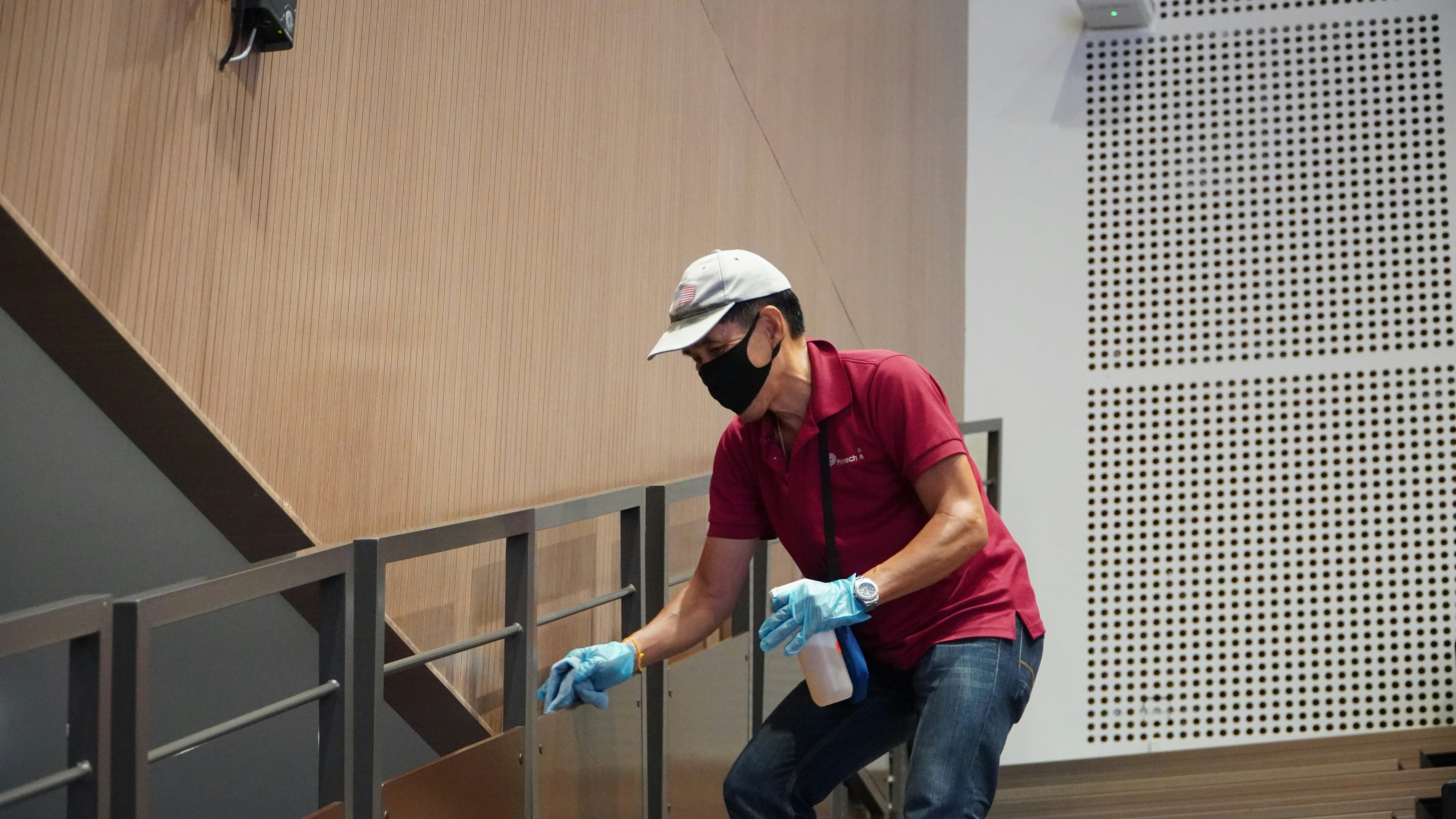 A GR Collins Commercial Cleaning team member disinfecting a handrail